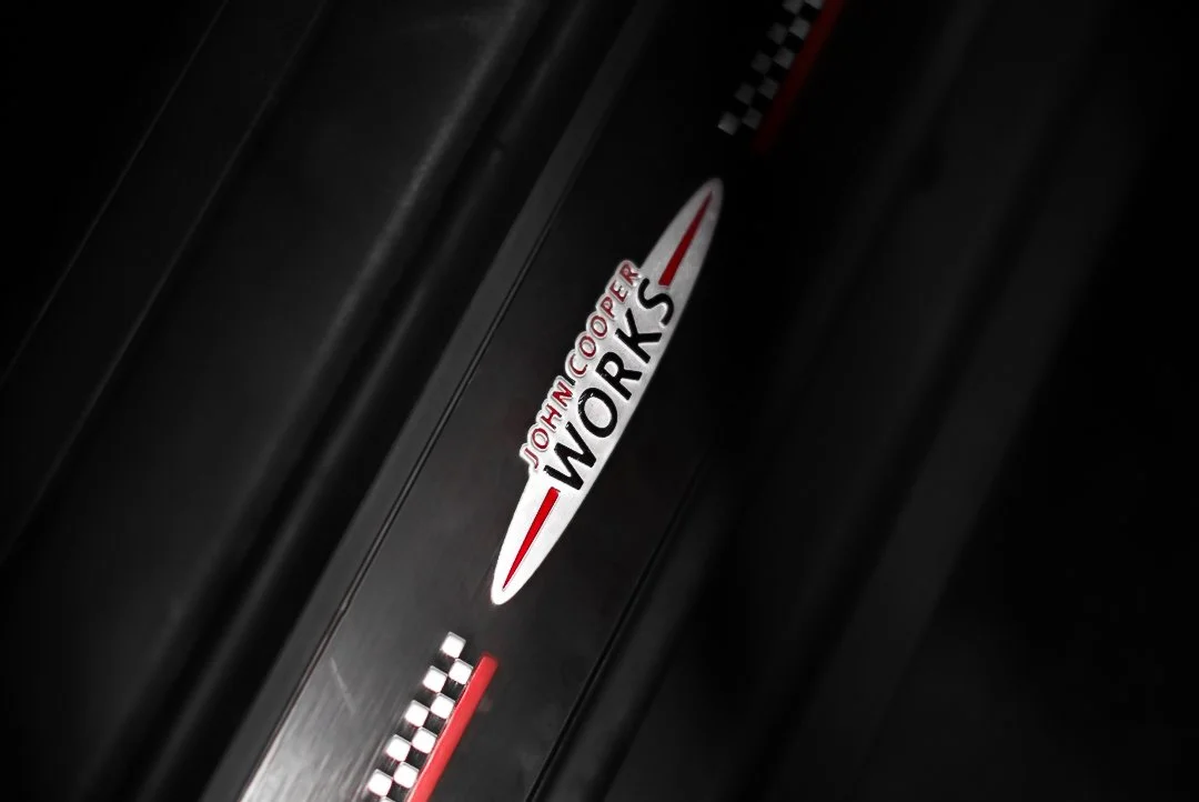 Close-up of a black machine with a logo that says Johnson Cooper WORKS with a checkered flag design.