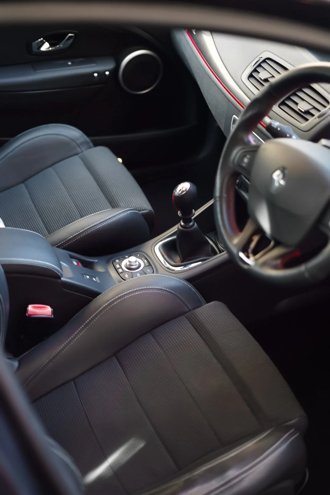 Interior of a car showing the front seats, steering wheel, gear shift, and dashboard with air vents.