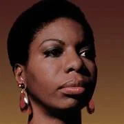 Close-up of Nina Simone, wearing large earrings, and looking slightly to the side.