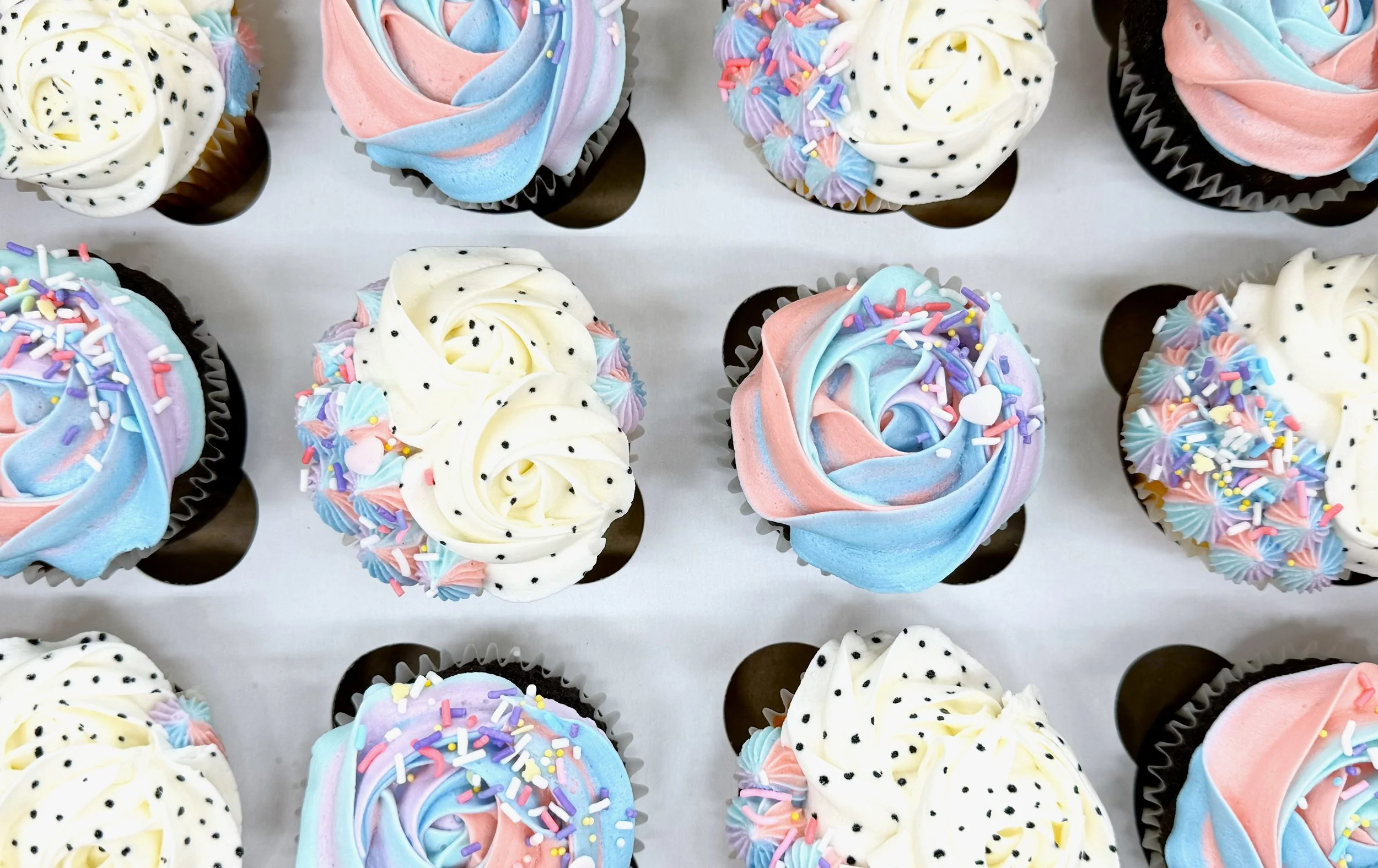 Assorted cupcakes decorated with colorful frosting and sprinkles.