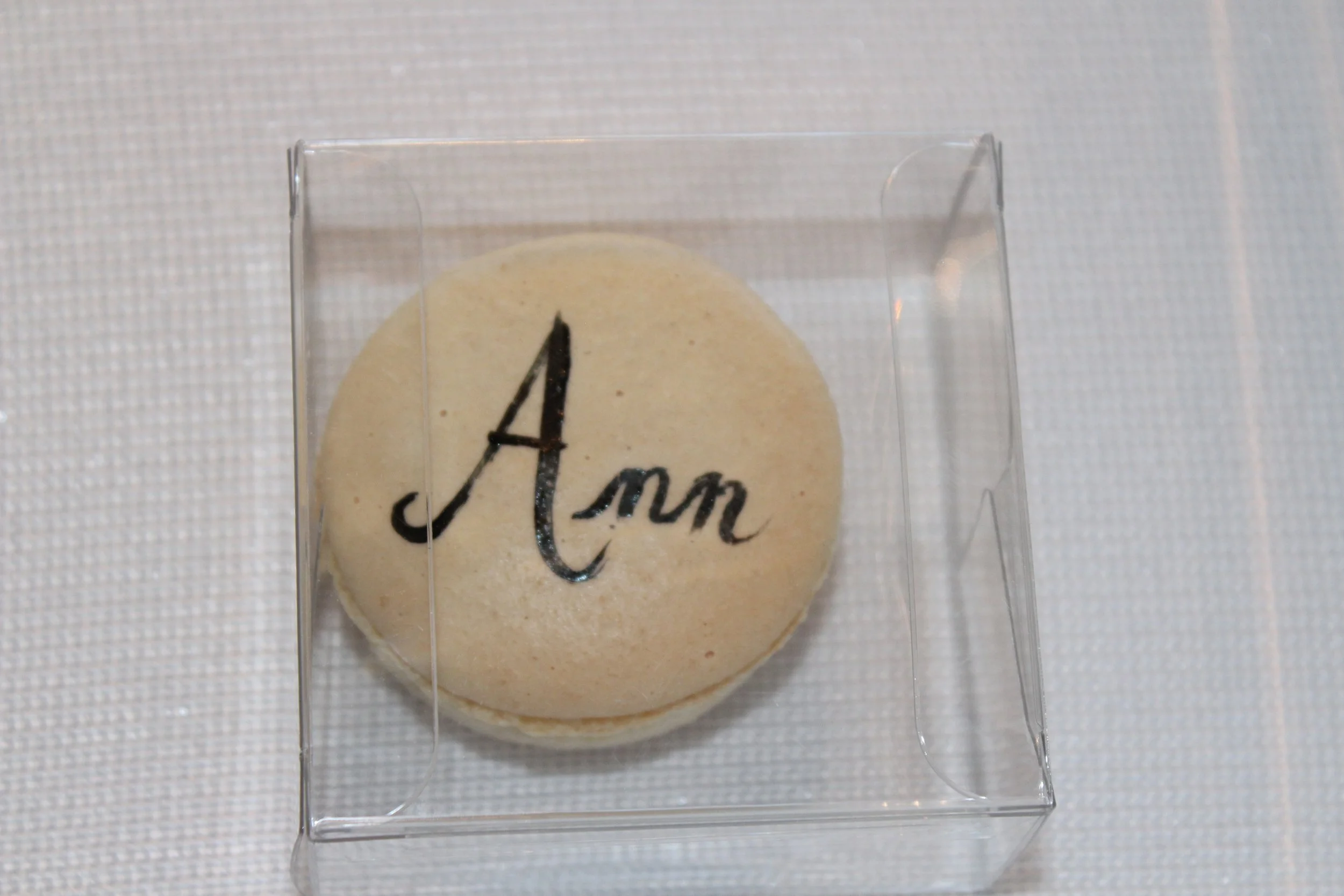 White macaron with black icing writing.