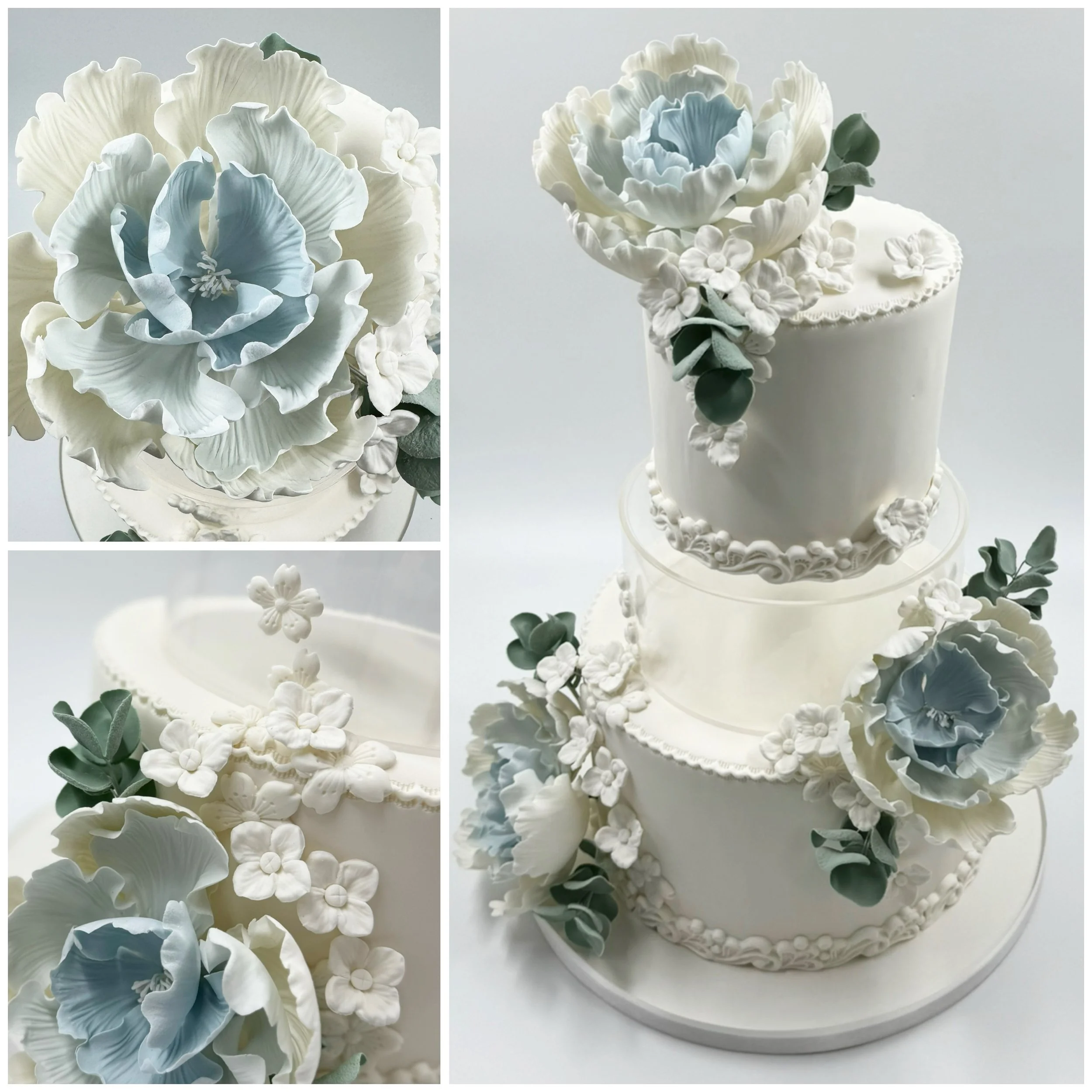 Three-tier white wedding cake decorated with white and light blue sugar flowers and green leaves.