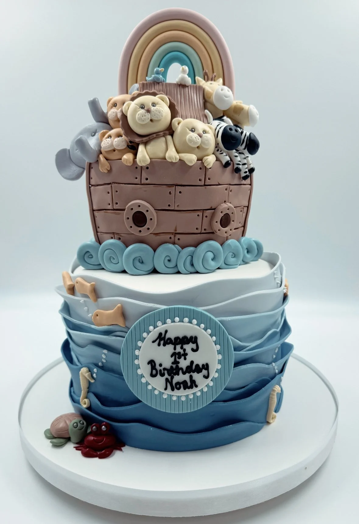 A multi-layered birthday cake decorated with sea animals and a rainbow.