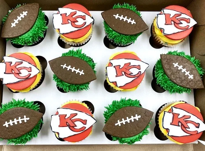 Football-themed cupcakes with Kansas City Chiefs logo decorations and football-shaped toppers.