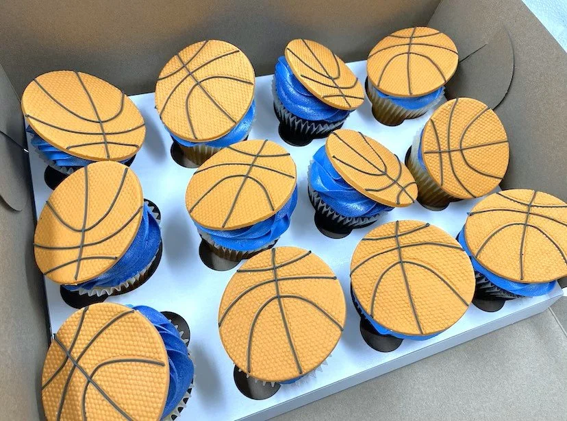 Cupcakes decorated with basketball-themed toppers.