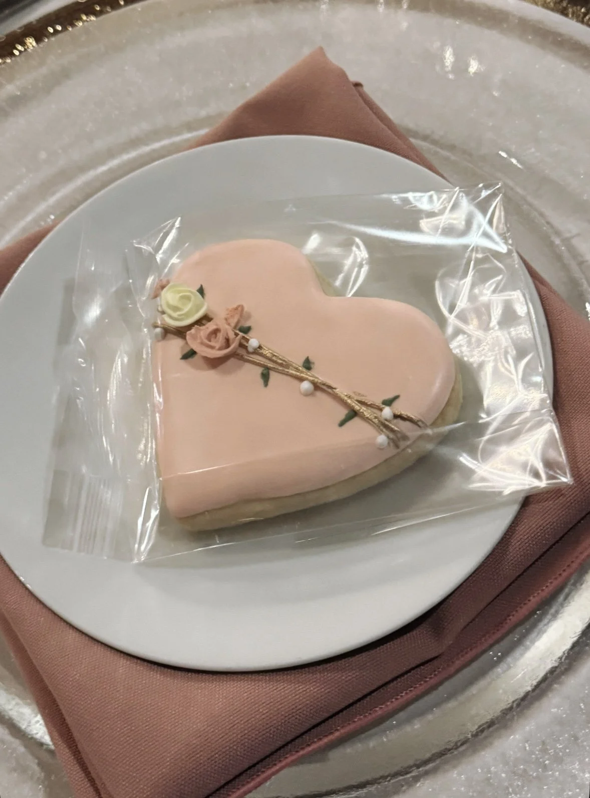 A heart-shaped pink cookie with floral decorations.
