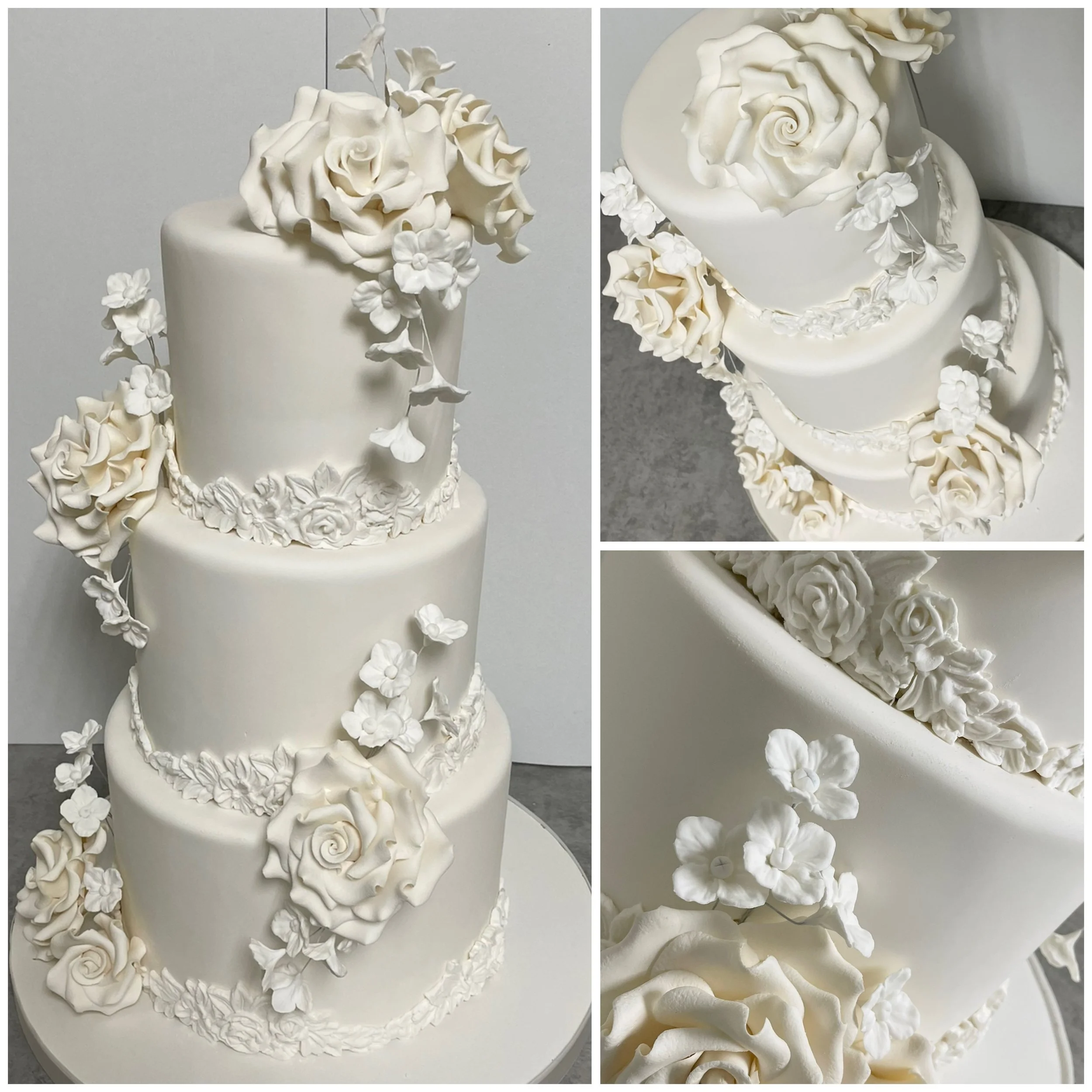A three-tier white wedding cake decorated with white roses and small flowers.