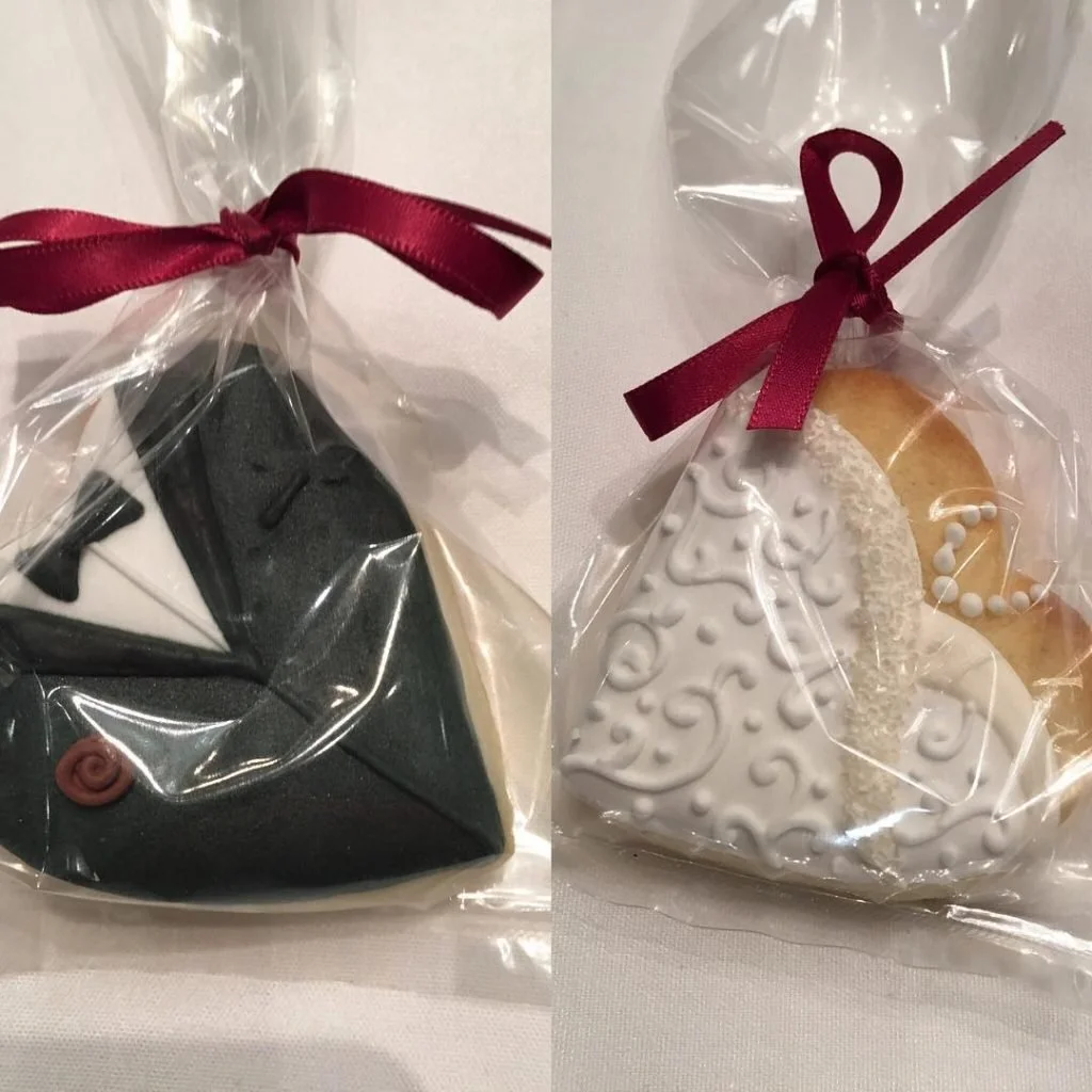 Cookies decorated with icing and wrapped in clear plastic with a red ribbon.