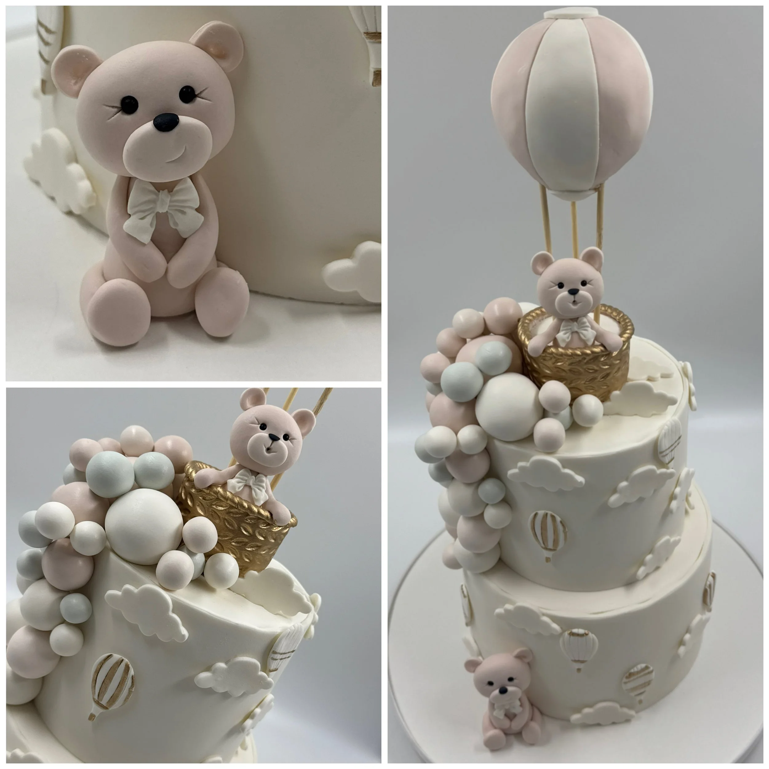 A three-tiered white cake decorated with clouds and hot air balloons, featuring teddy bear toppers in baskets attached to a balloon, with a teddy bear sitting on the cake base.
