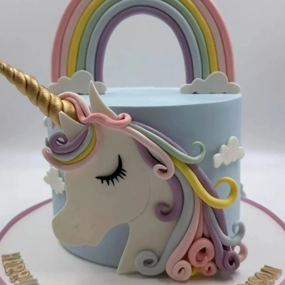 Colorful unicorn-themed cake with pastel rainbow and clouds design.
