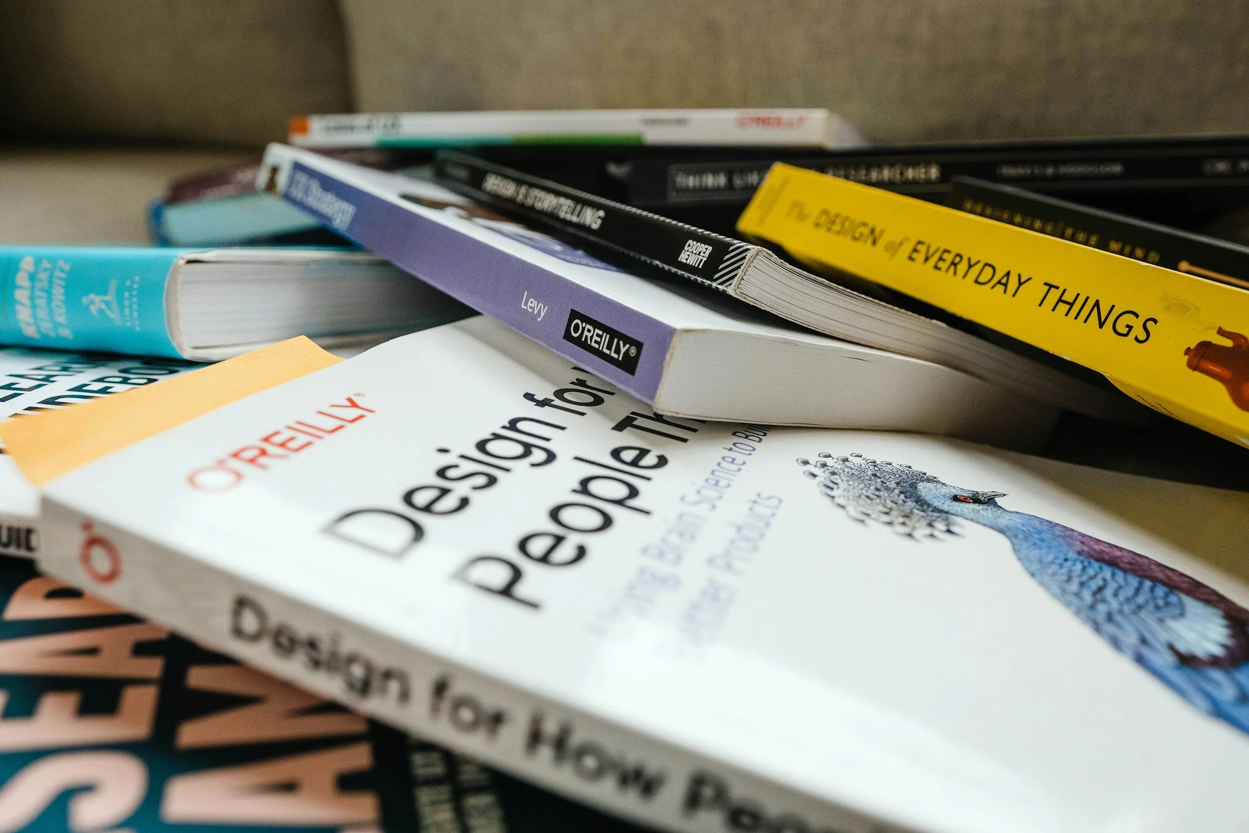 Close-up of various books stacked on top of each other, including 'Design for People' and 'The Design of Everyday Things'.