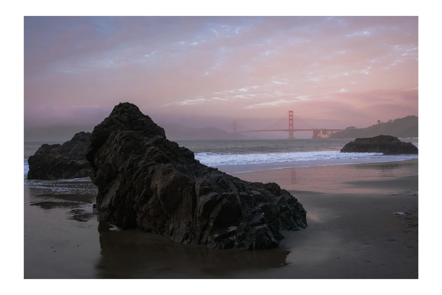 China Beach sunset, pink sky, Golden Gate Bridge in the background, rocks in the foreground