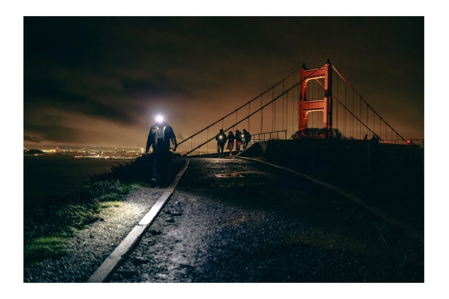 Night Golden Gate Bridge photo a man walking down with a light on his head