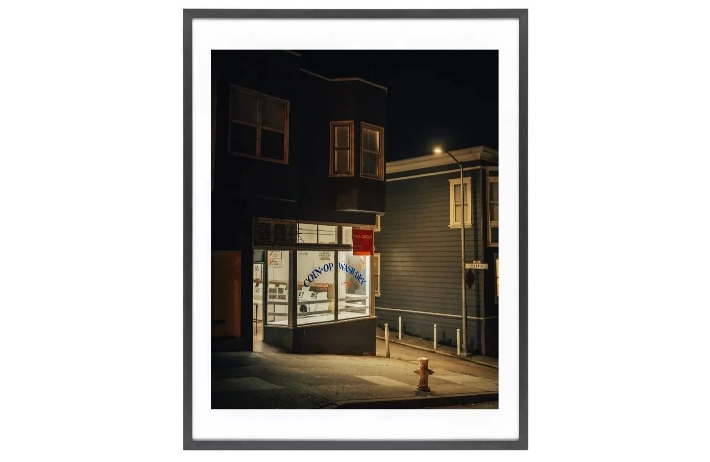 Night photo print of a lit laundromat in North Beach, San Francisco, glowing under a street lamp.