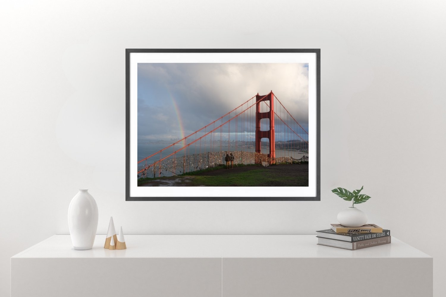 Golden Gate Bridge viewed from Battery Spencer with a rainbow beside one beam and two people standing and looking at it.