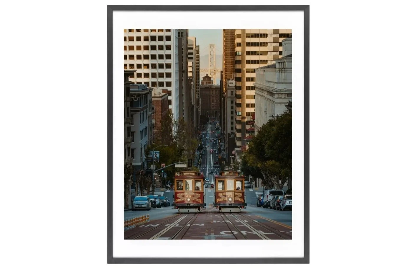Fine art print of two San Francisco cable cars passing on California Street with the Bay Bridge in the background.