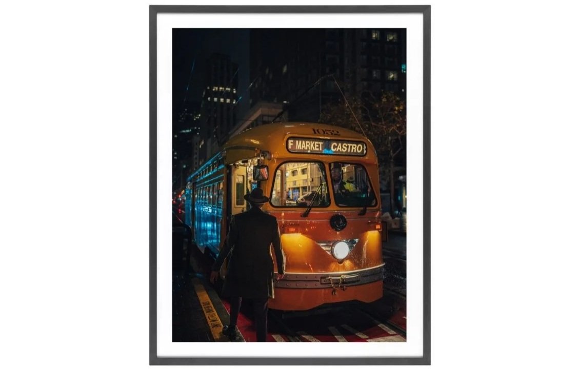 Yellow F Market & Castro streetcar in the rain with a man wearing a hat entering it.