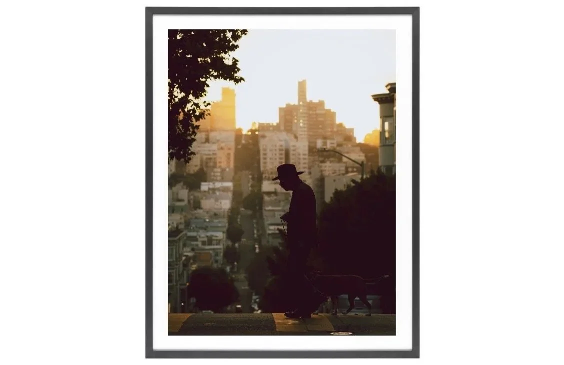 Silhouette of a man walking his dog on Grant Avenue in San Francisco at sunset with city skyline