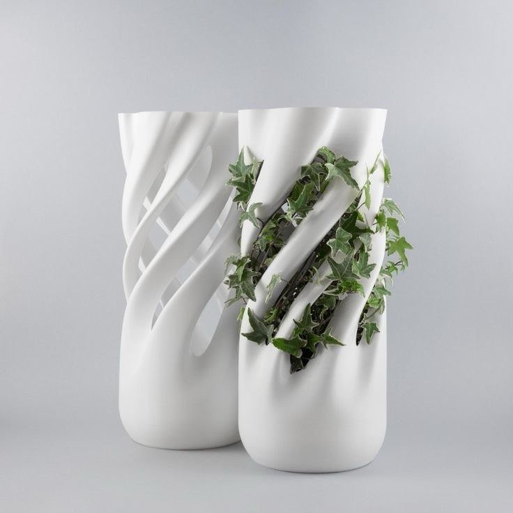 Two modern white vases with spiral and twisted designs, one containing ivy plant