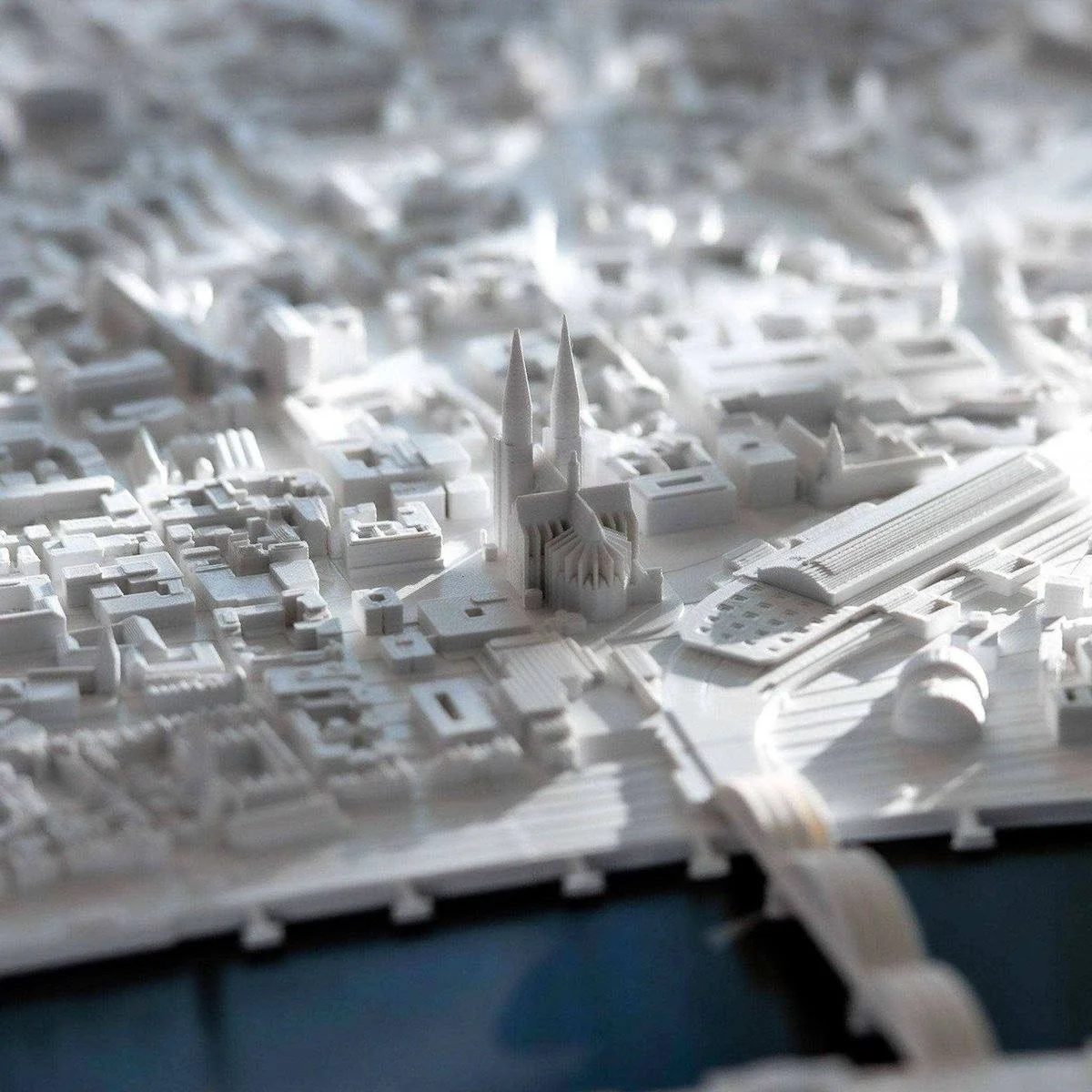 A detailed white architectural model of a city, featuring a large cathedral with two tall spires and various surrounding buildings.