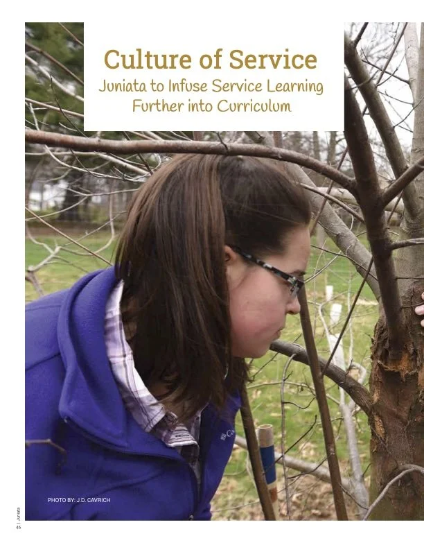 A woman in a blue jacket and glasses inspecting a tree outdoors. Feature article news writing reporting creative writing.