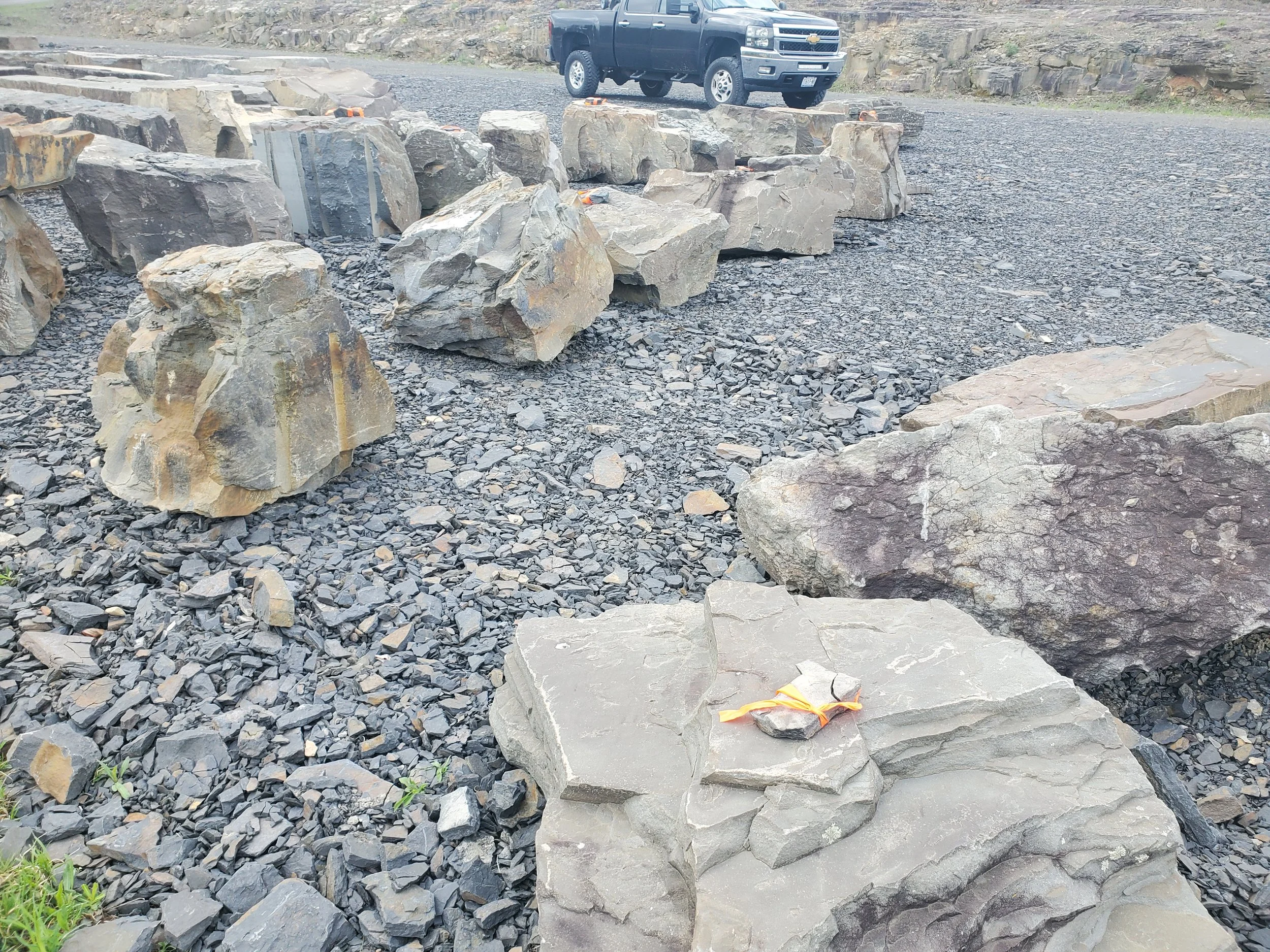Large rocks and gravel on a construction site, with a black pickup truck in the background.
