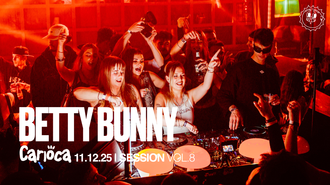 Crowd of young adults dancing and enjoying music at a nightclub or concert, with DJ equipment and vibrant red lighting.