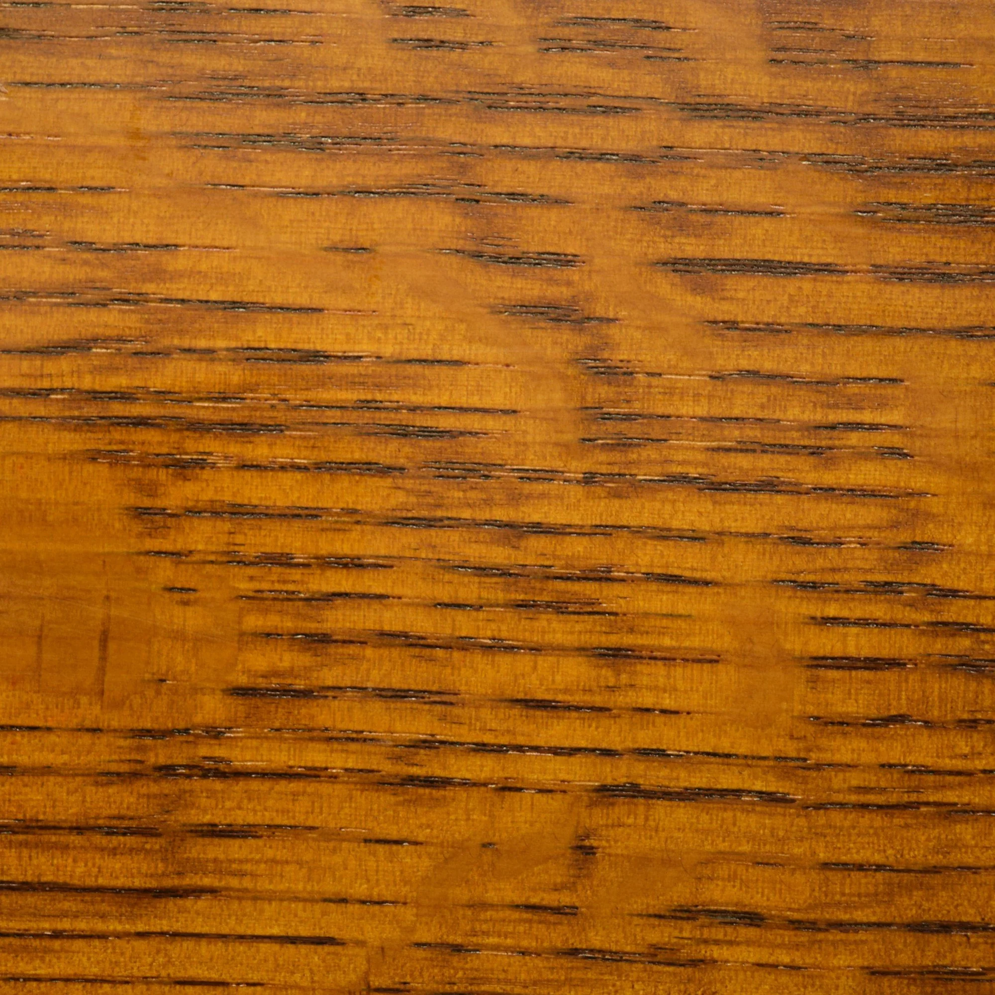 Close-up of a wooden surface with visible grain patterns and a warm brown color.