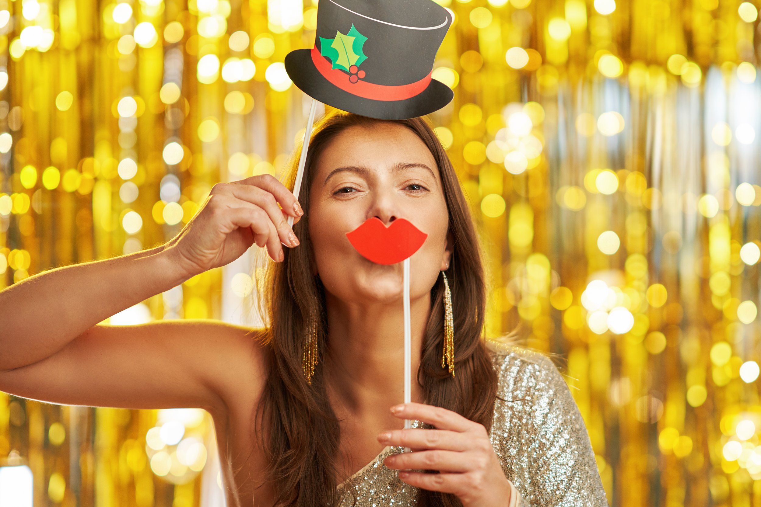 A guest posing with photo booth props in front of a gold backdrop, showcasing a fun and engaging event experience.