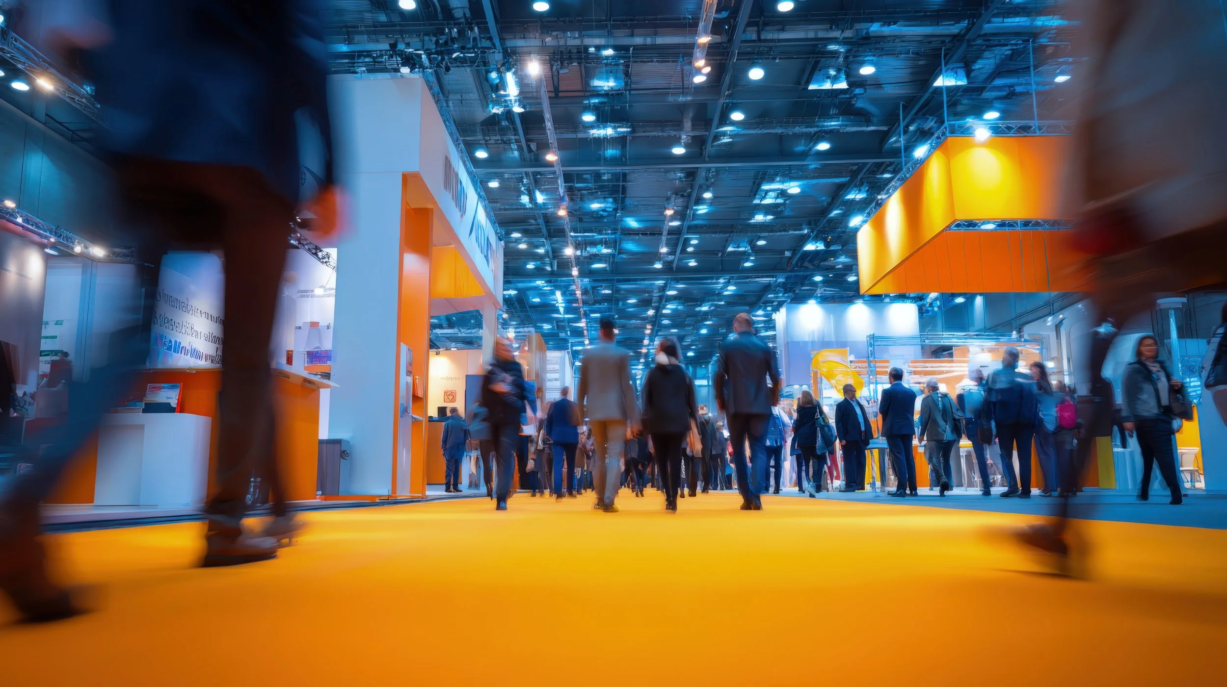 Attendees walking through a busy trade show floor inside a large convention exhibit hall