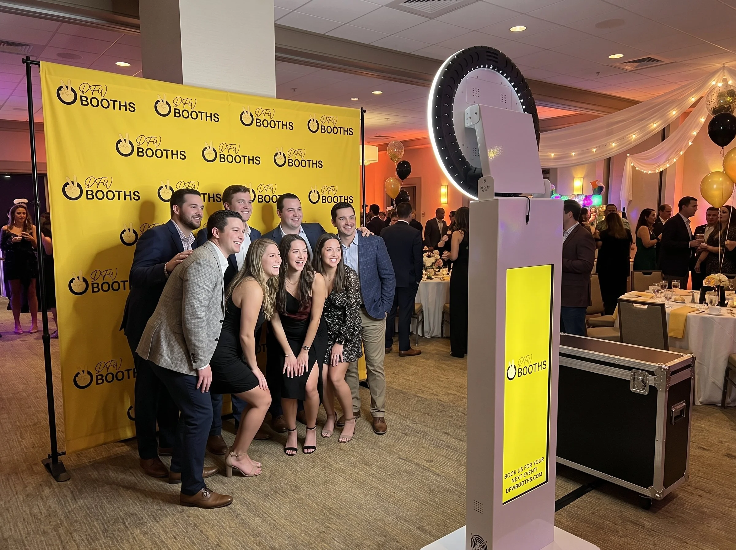 Guests posing in front of a gray backdrop with the DFW Booths digital selfie podium photo booth and halo ring light at an event