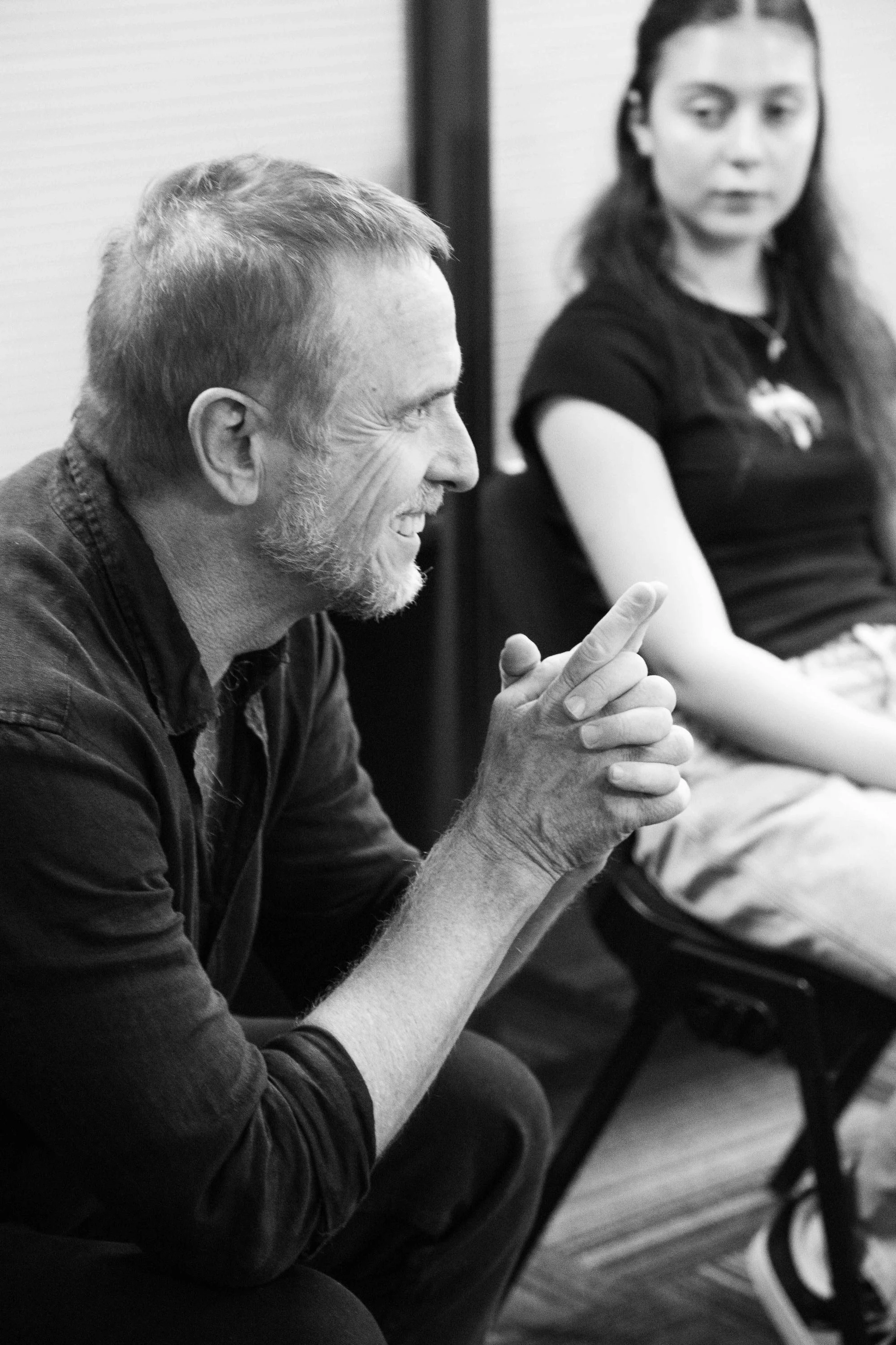 Richard Lindsell Director and Tutor at The Actors Class talking, sitting on a chair with a acting student  sitting beside him, in an indoor setting.