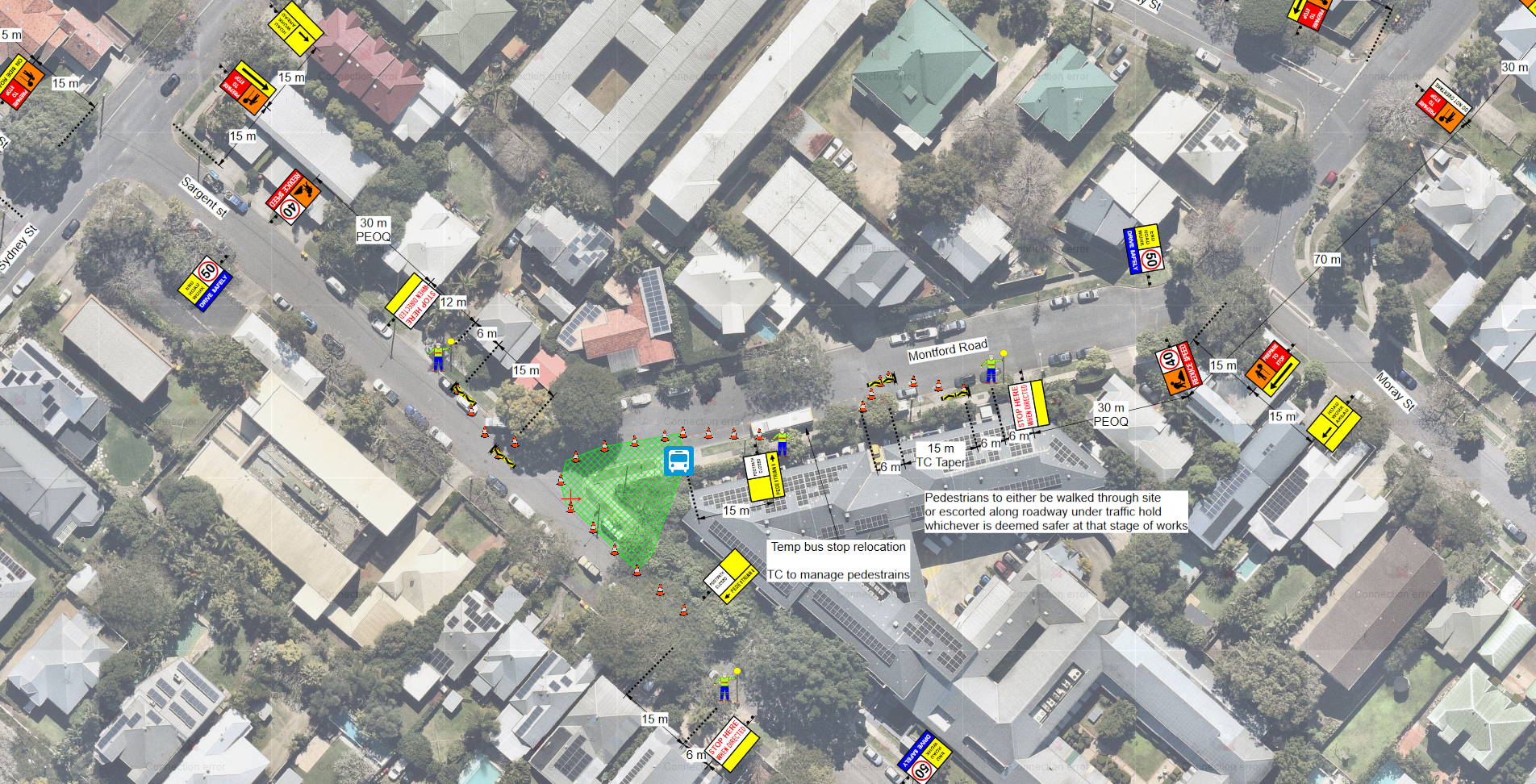 Aerial view of a residential neighborhood with a street marked for roadwork construction. Traffic signs, cones, and workers are visible, indicating road closure and detours. There are trees, houses, and parked cars along the streets.