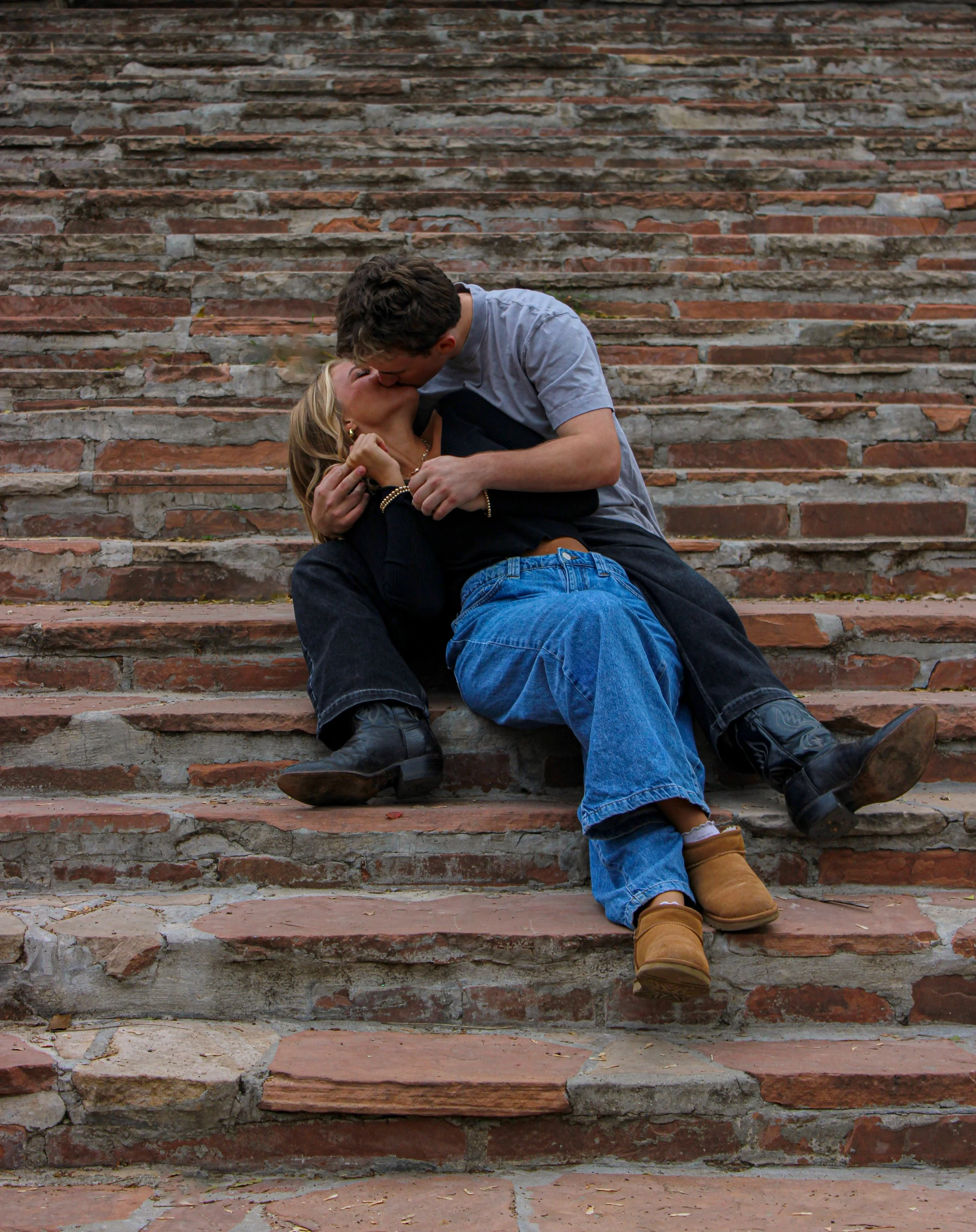 A young couple sharing a kiss on stone steps.