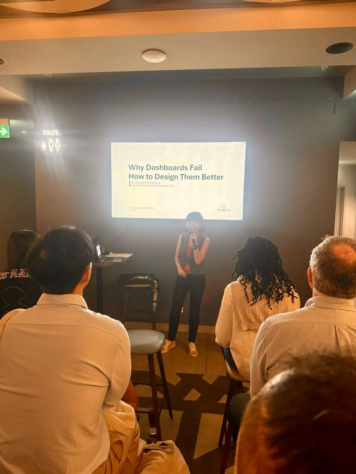 Danni Liu presenting "Why Dashboards Fail, and How to Design Them Better" to a full room.