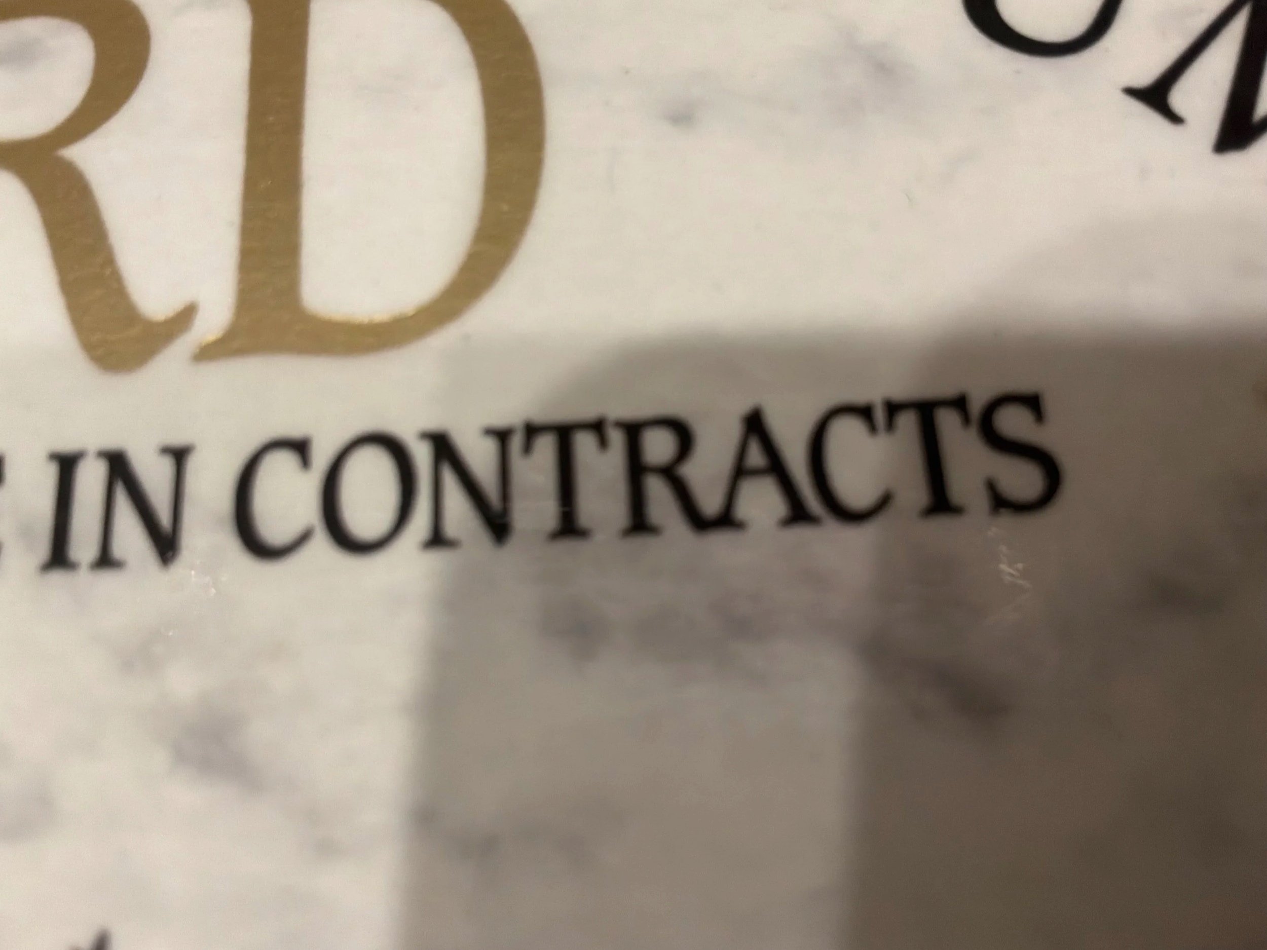 Close-up of a printed page showing the words 'IN CONTRACTS' and part of a large gold letter.