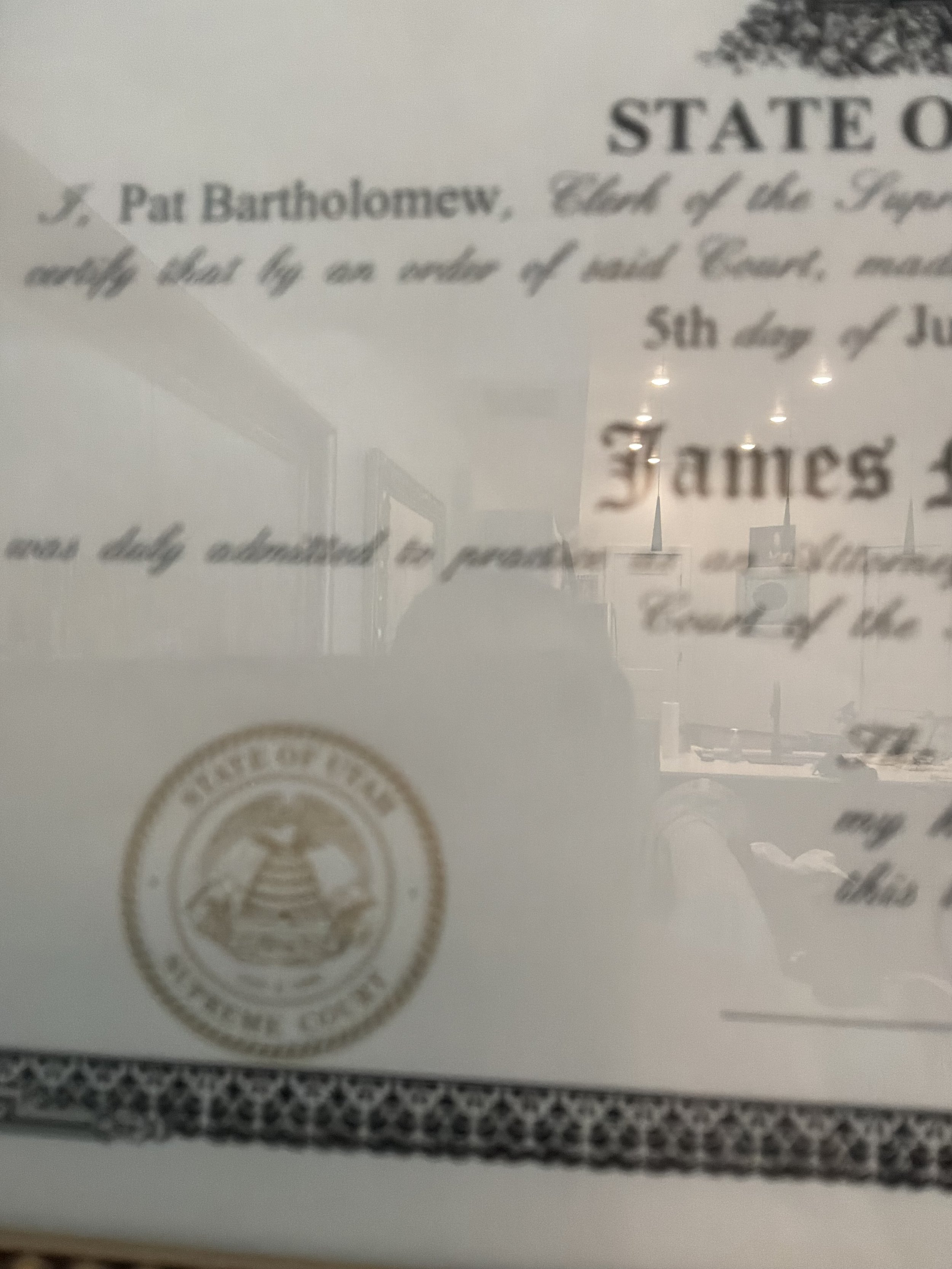 Close-up of a document with text and a seal, viewed through a reflective surface.