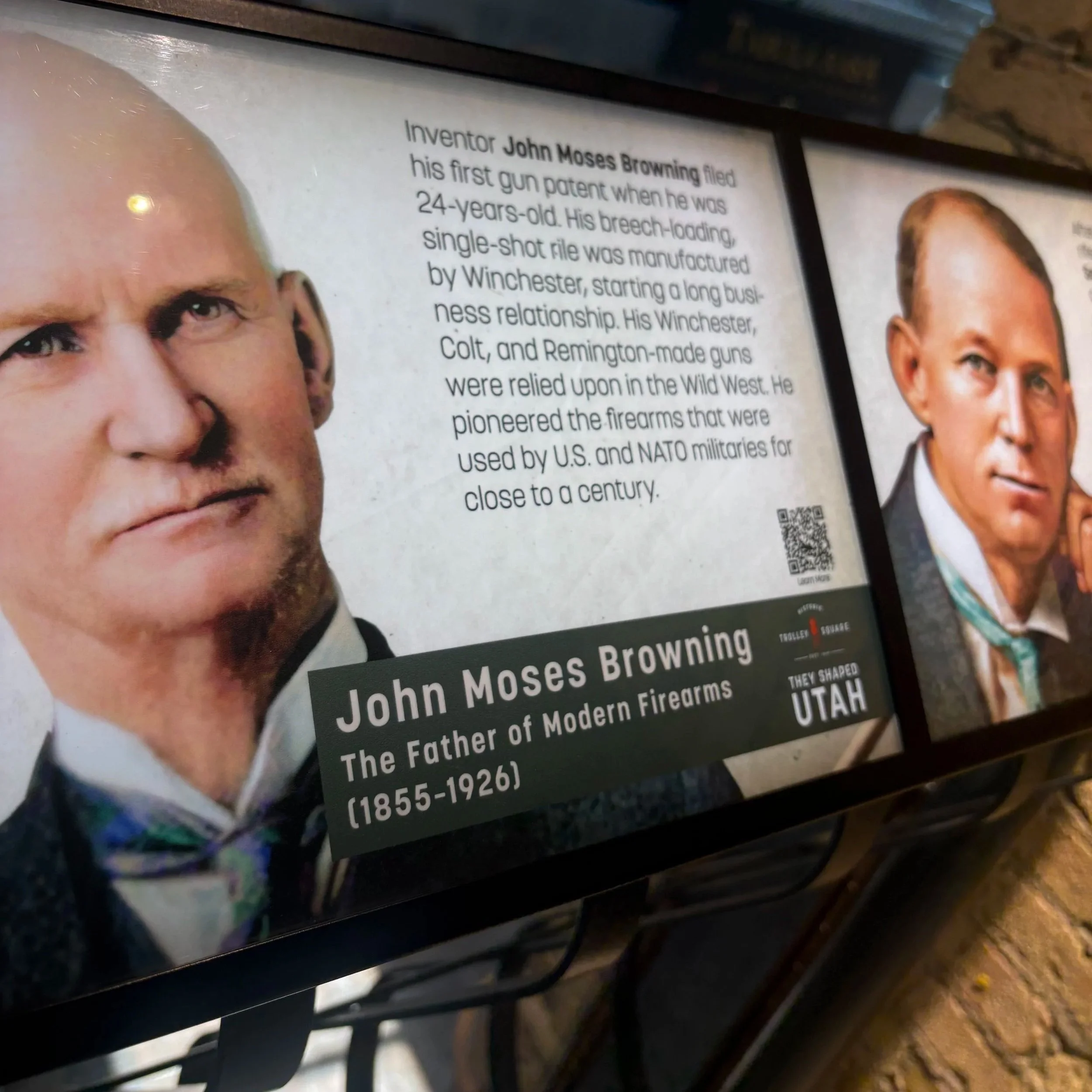 Close-up of a bench with a plaque featuring a photo of John Moses Browning and text about his life and inventions.