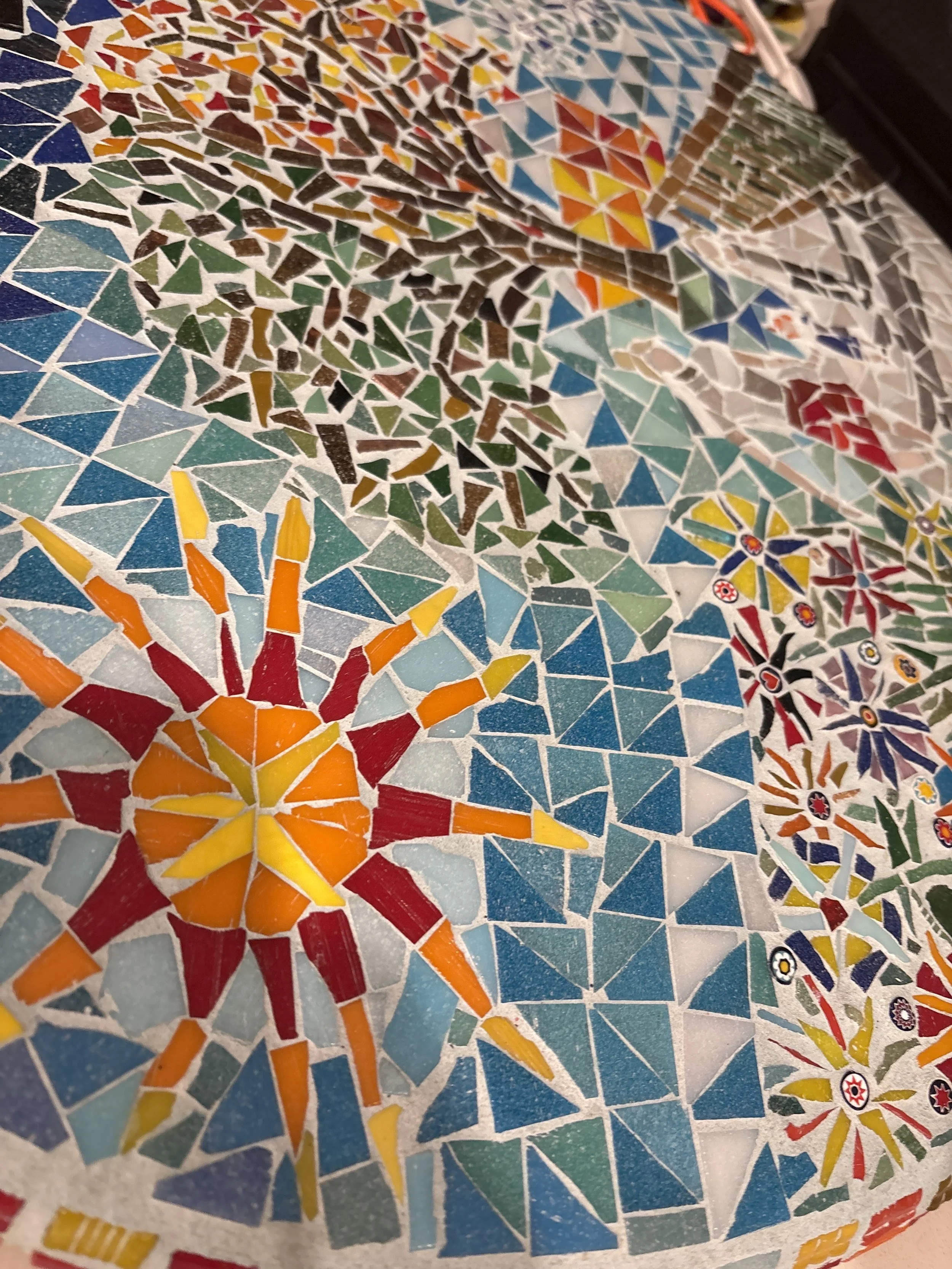 A colorful mosaic with floral and geometric patterns in various colors such as red, yellow, blue, and green.
