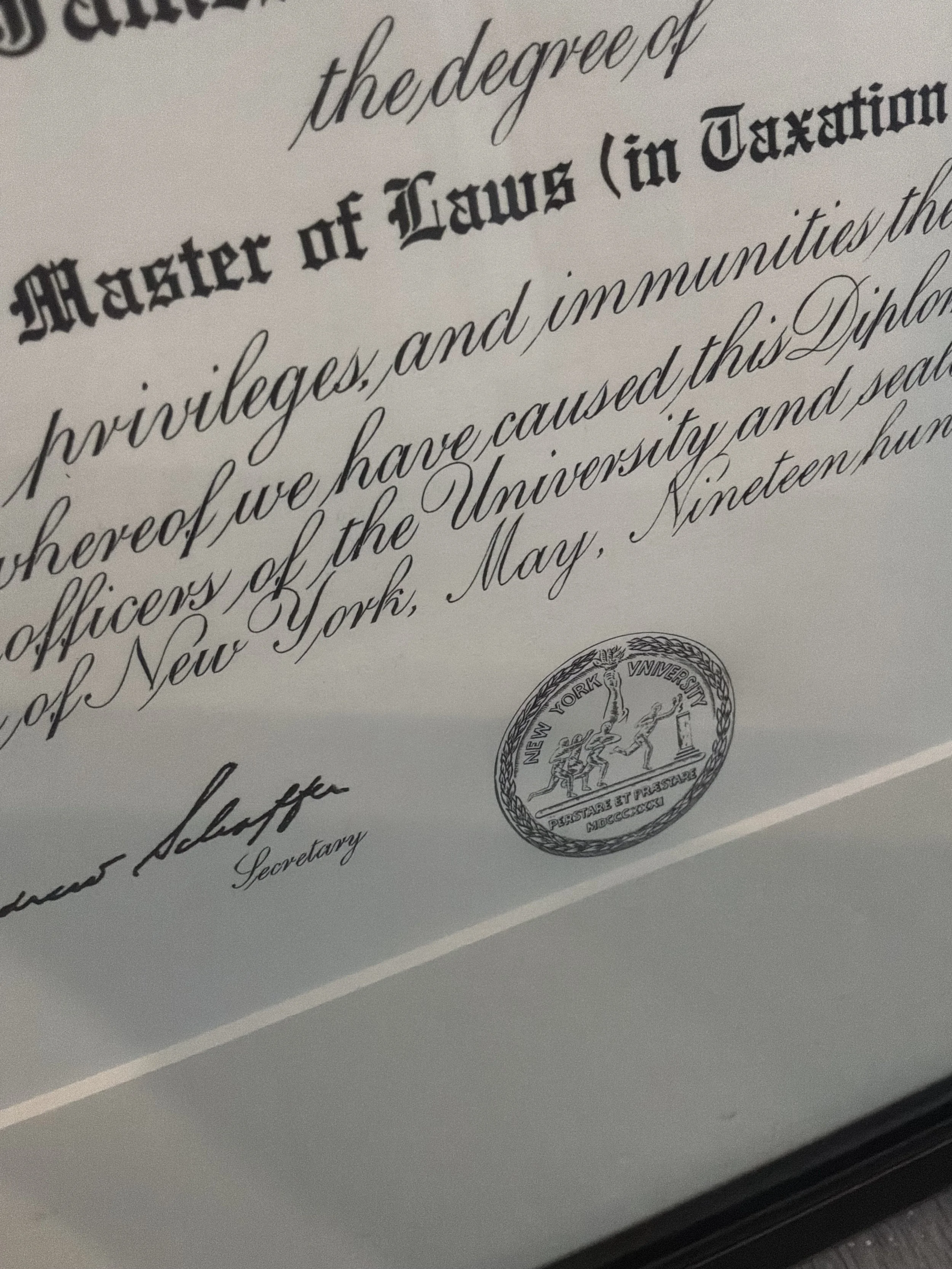 Close-up of a formal certificate with decorative cursive script and bold gothic text, featuring a seal or emblem from New York University.