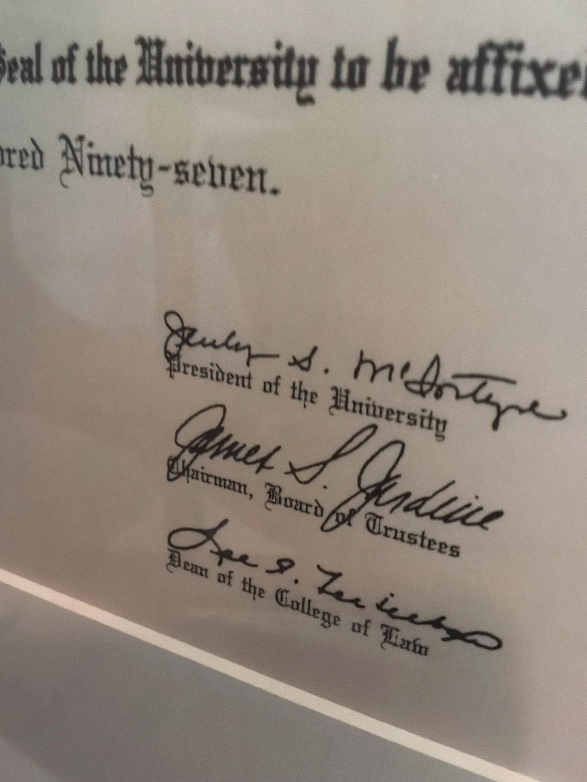 Close-up of a handwritten or printed document featuring a signature at the bottom, with some text in a formal, old-fashioned font.