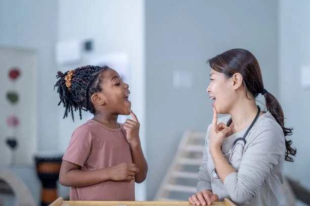 A young girl and female doctor smiling and talking in a medical office.