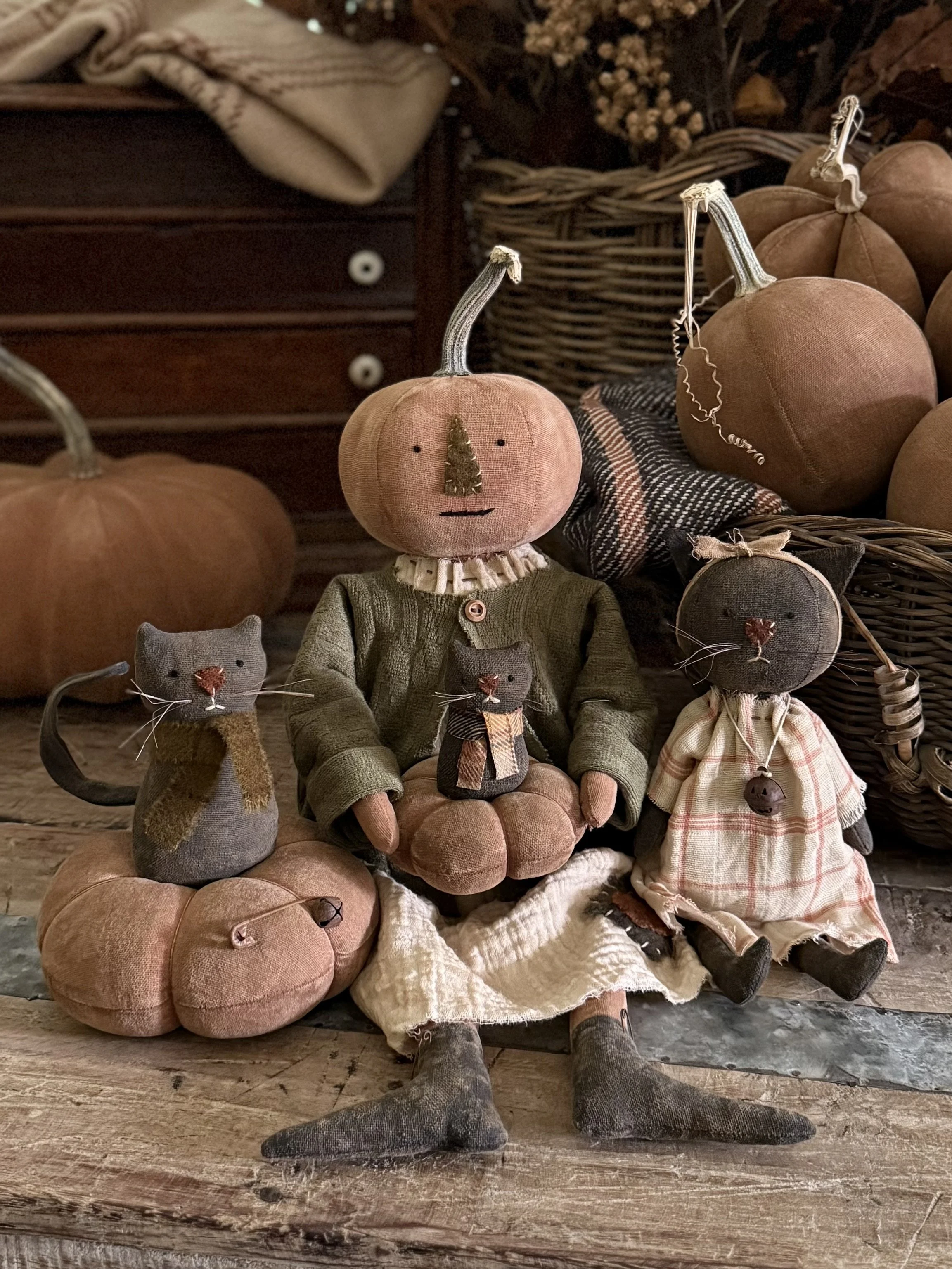 Decorative pumpkin figures with stuffed animal characters, including a pumpkin-headed figure with a scarf and two mouse-like figures, set in autumn themed display with pumpkins and pumpkins in the background.