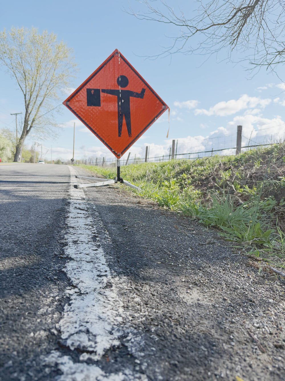 Road construction sign indicating roadwork ahead, with a silhouette of a person holding a flag.