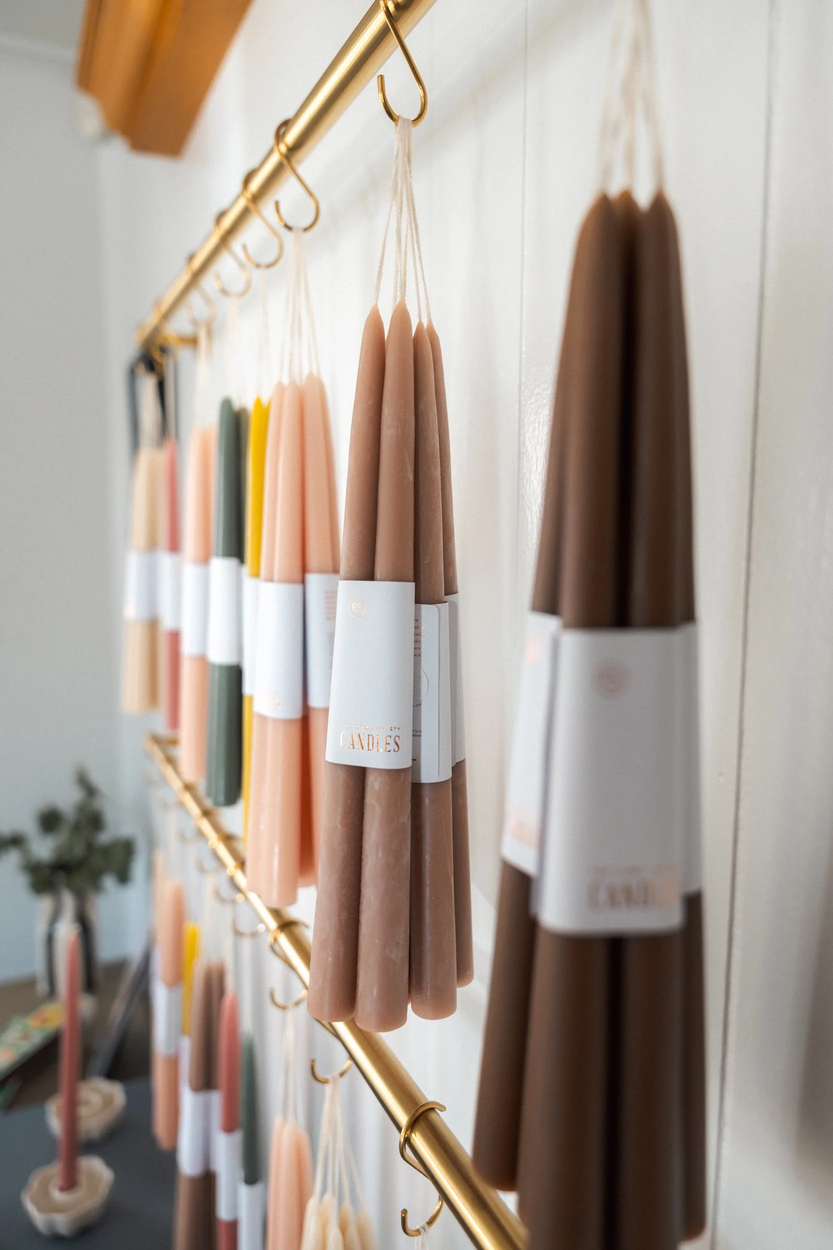 Colorful candles hanging on a gold rod in a home decor display.