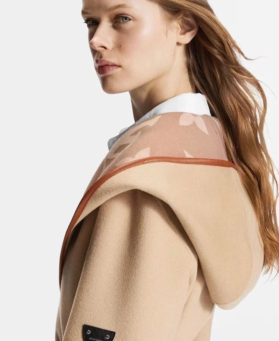 The Muse Edit. Outfit inspiration using our latest finds. A woman with red hair looking over her shoulder, wearing a beige coat with a hood and a patterned scarf.