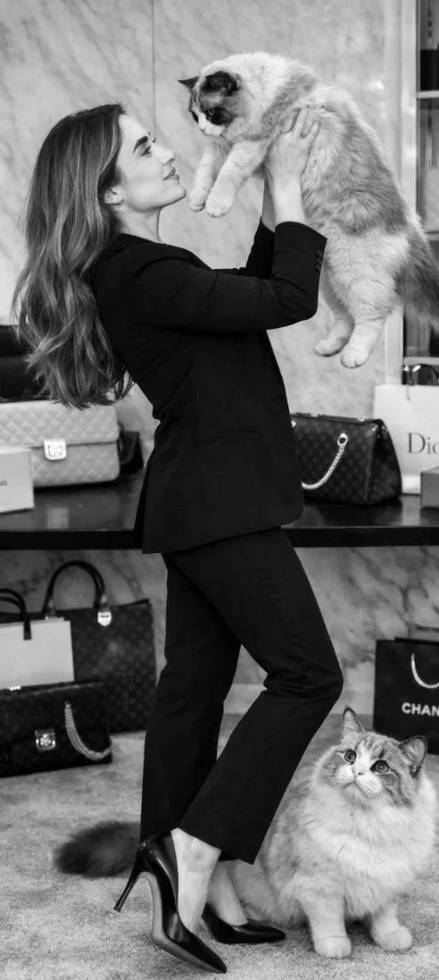 Founder of The Muse Edit holding her cat in luxury resale showroom with authenticated designer handbags