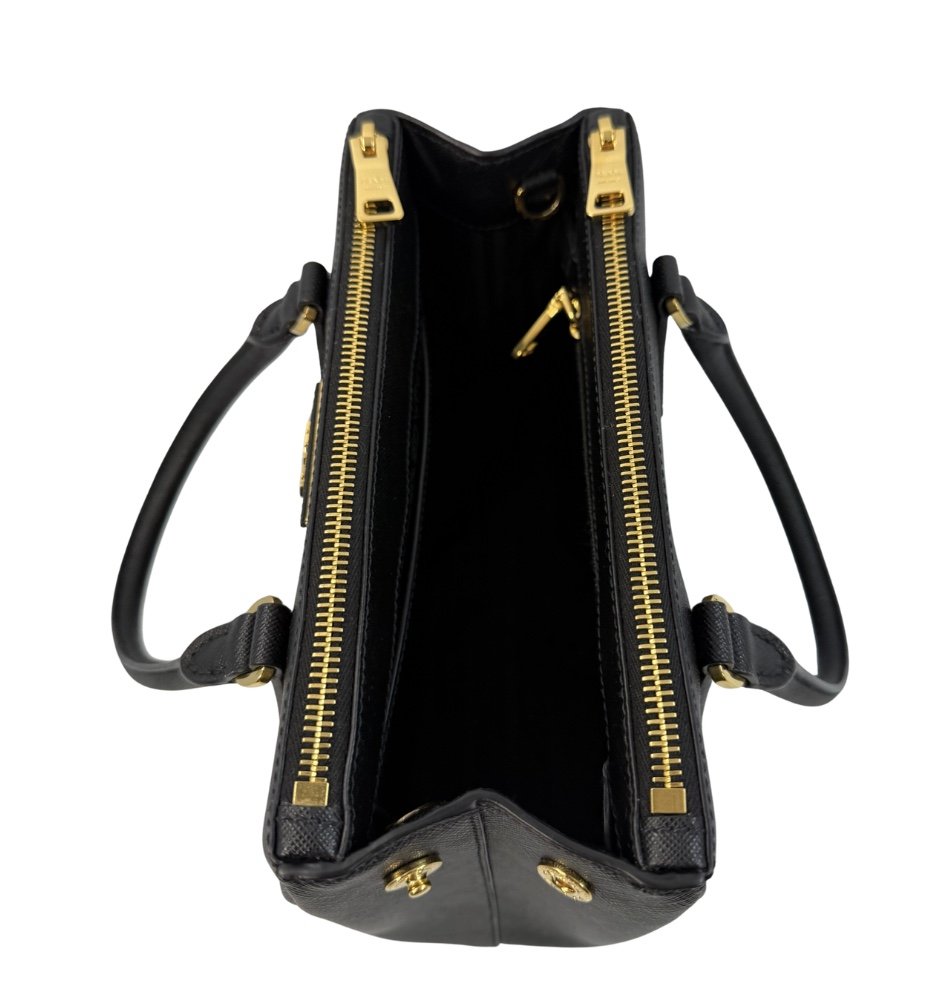 Open black handbag with gold zipper and handles, empty interior, viewed from above.