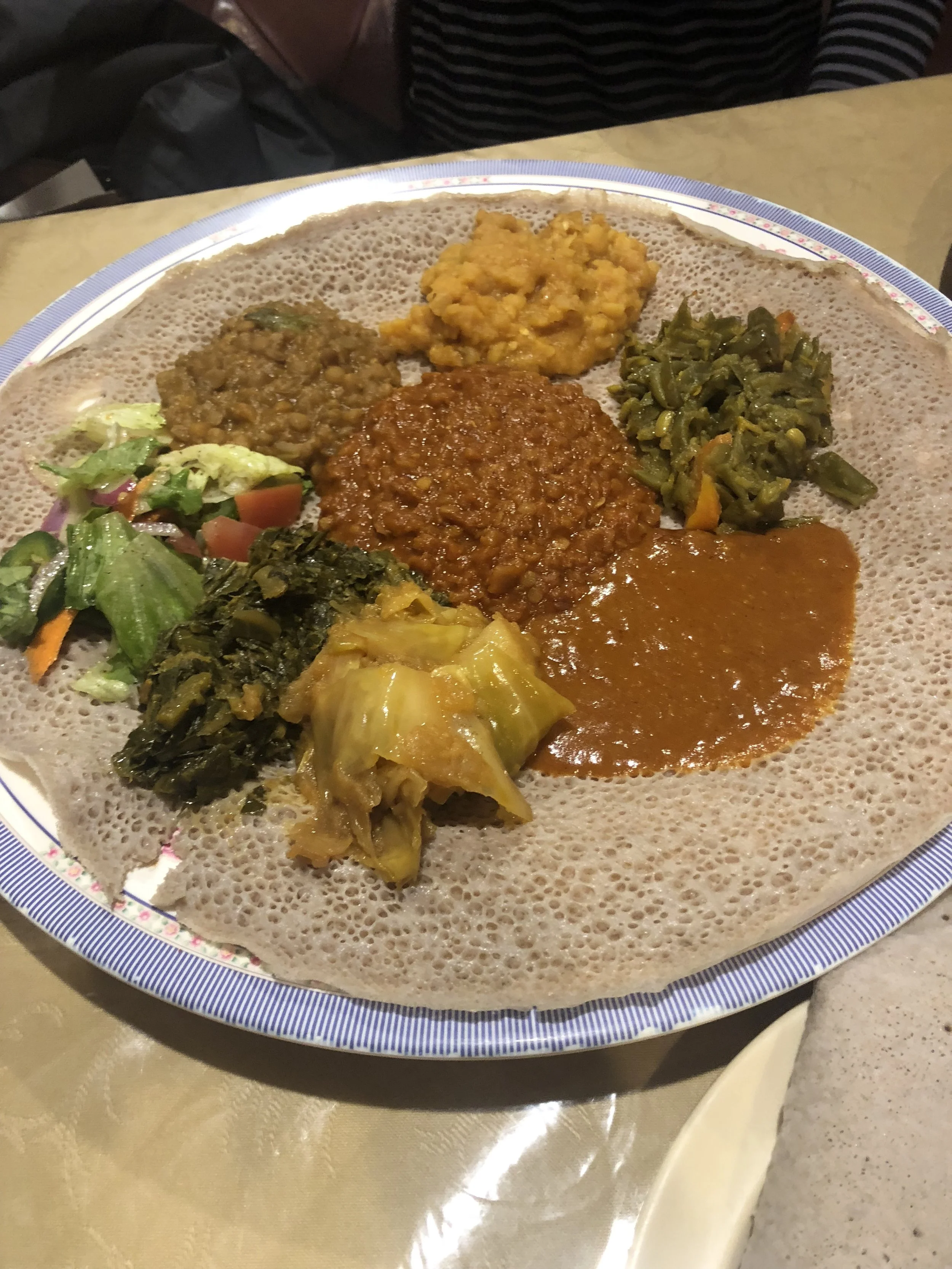 Ethiopian injera plate with assorted vegetable and lentil dishes.