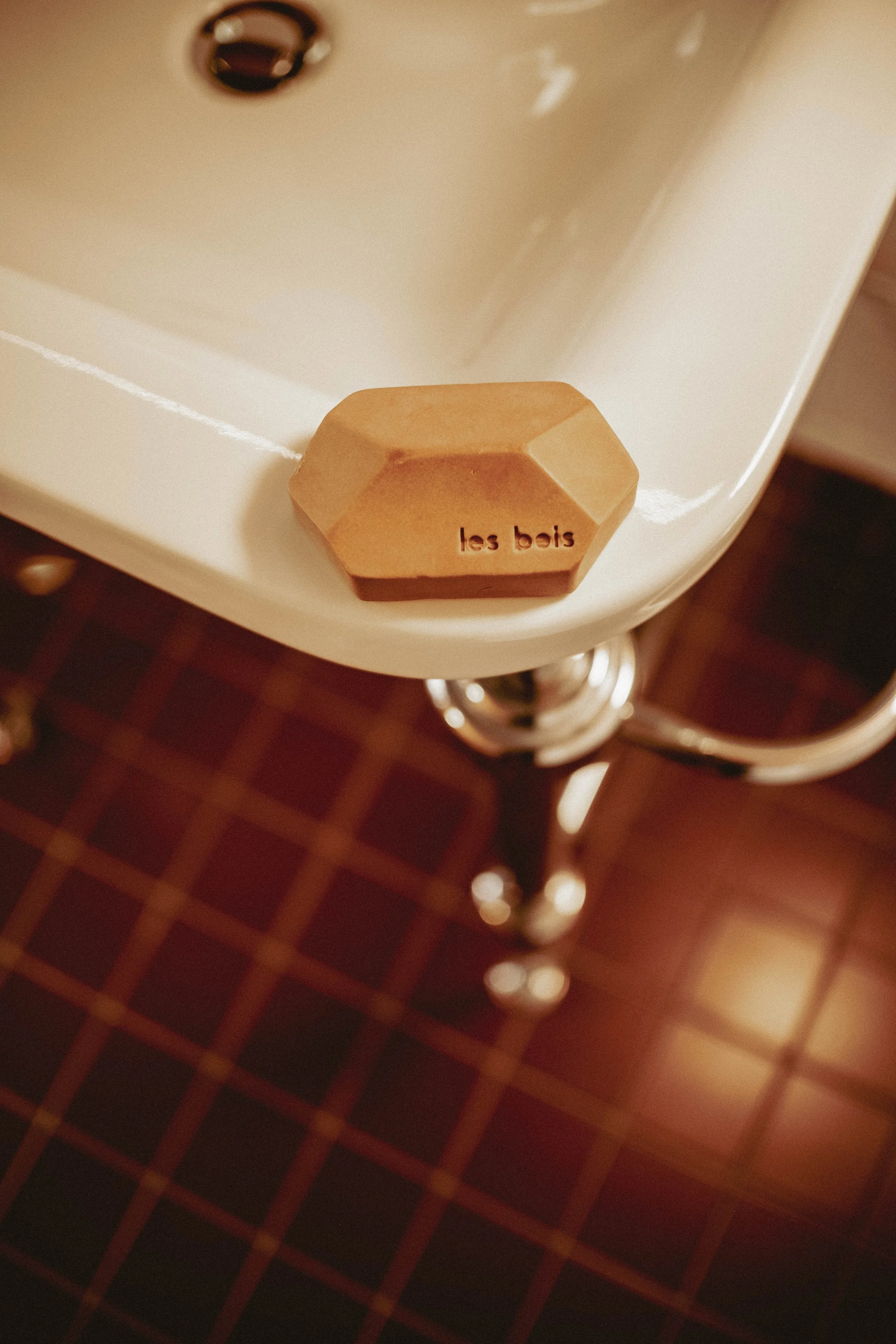 Une pierre décorative beige posée sur une surface blanche, avec l'inscription 'les bois', dans un intérieur avec un sol en carreaux marron.